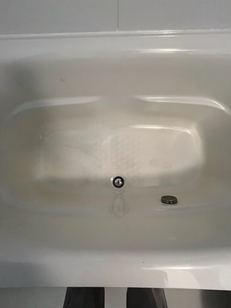 入浴剤や汚れの蓄積によって変色・黄ばみが見られる人工大理石浴槽底面の拡大写真