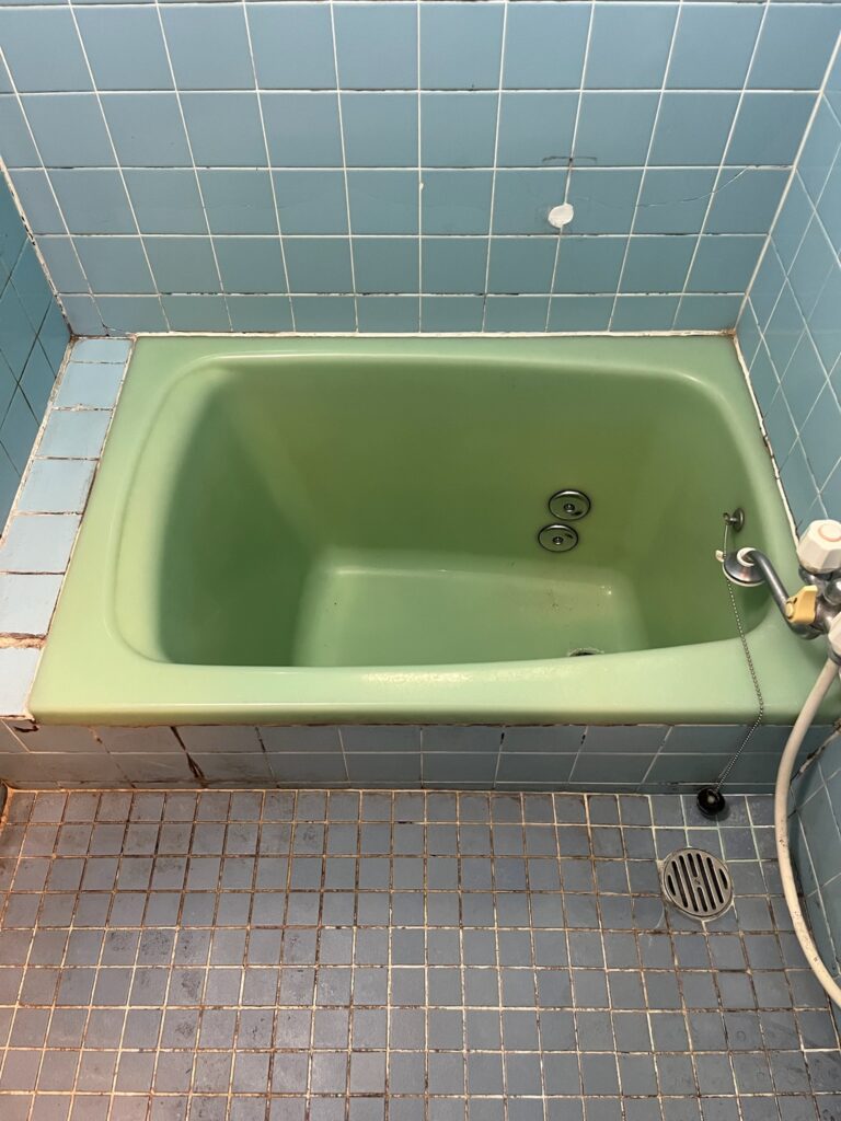 施工前の在来浴室。タイルの目地に汚れがたまり、緑色の浴槽が古さを感じさせる